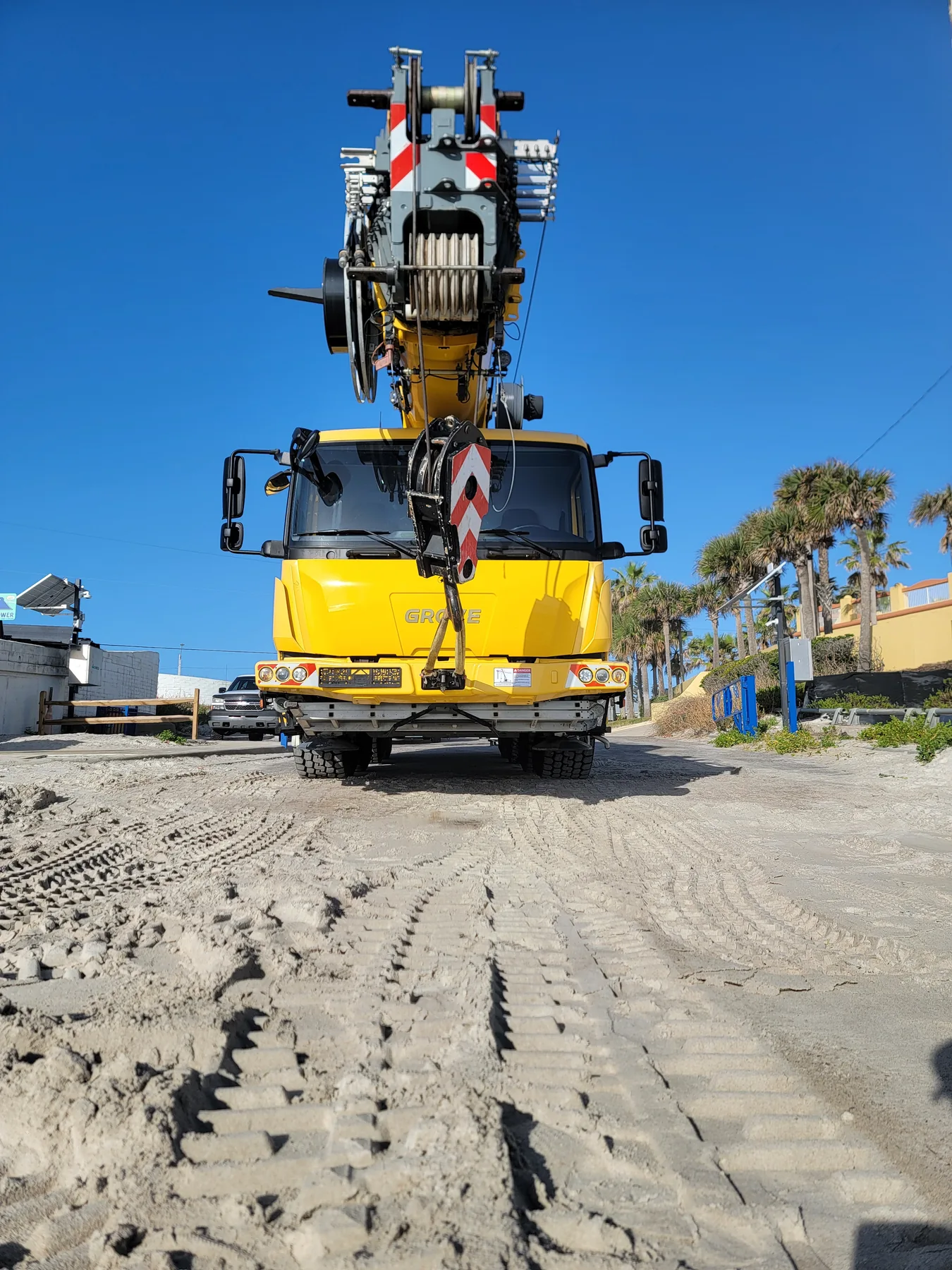 Head-on view of a yellow Faletti crane with the winch above the cab and a striped hook block in front.