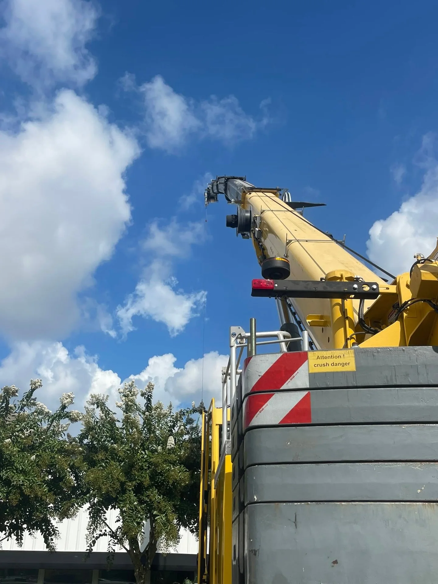 View upward past the counterweights and yellow boom of a crane against the sky.