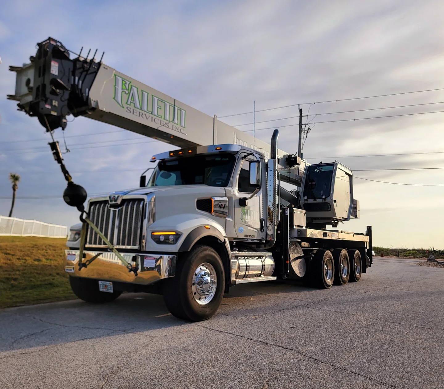 Faletti-branded white truck-mounted crane with its boom positioned over the cab.