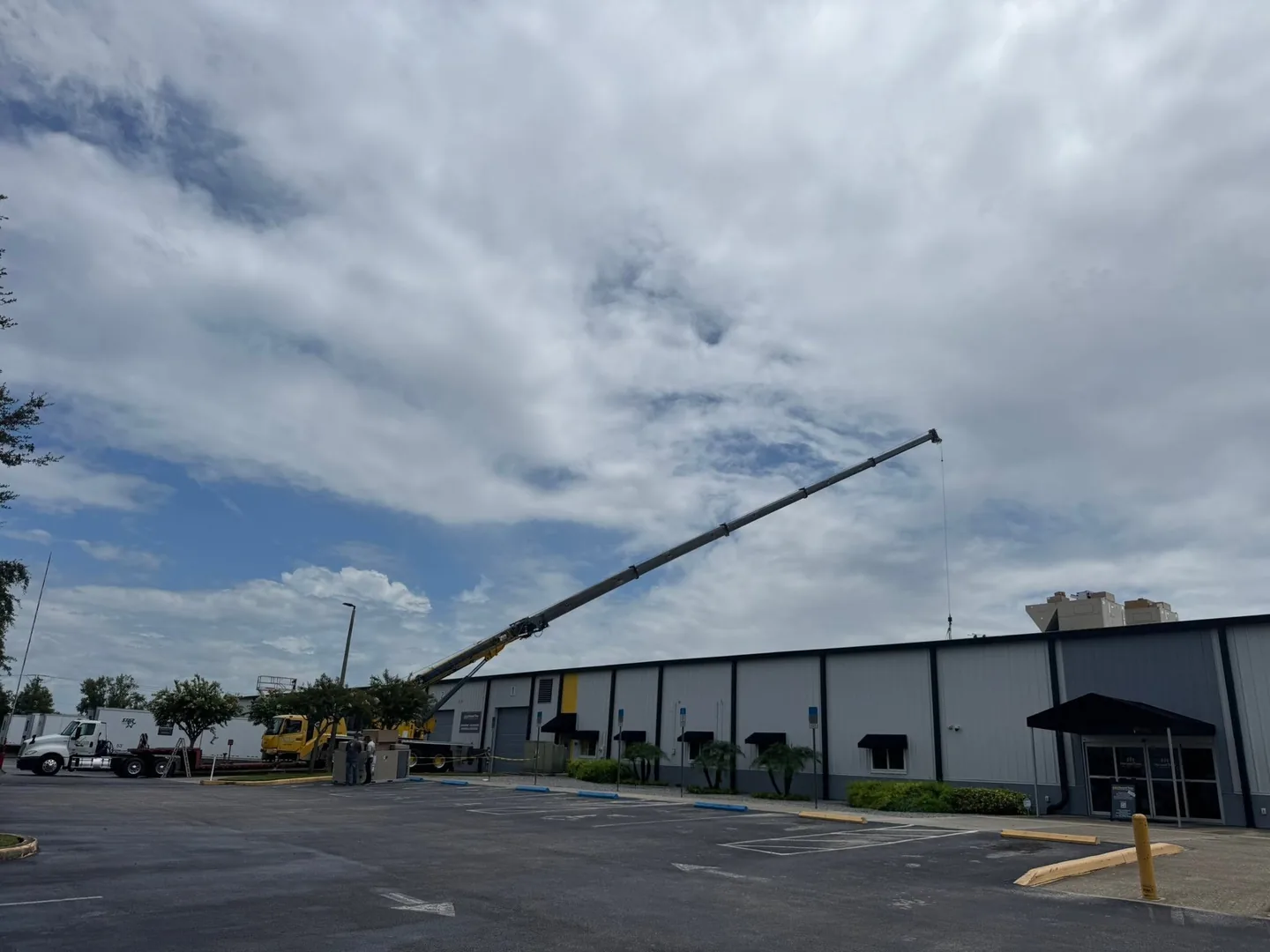 Yellow crane extending its boom over a large industrial building.