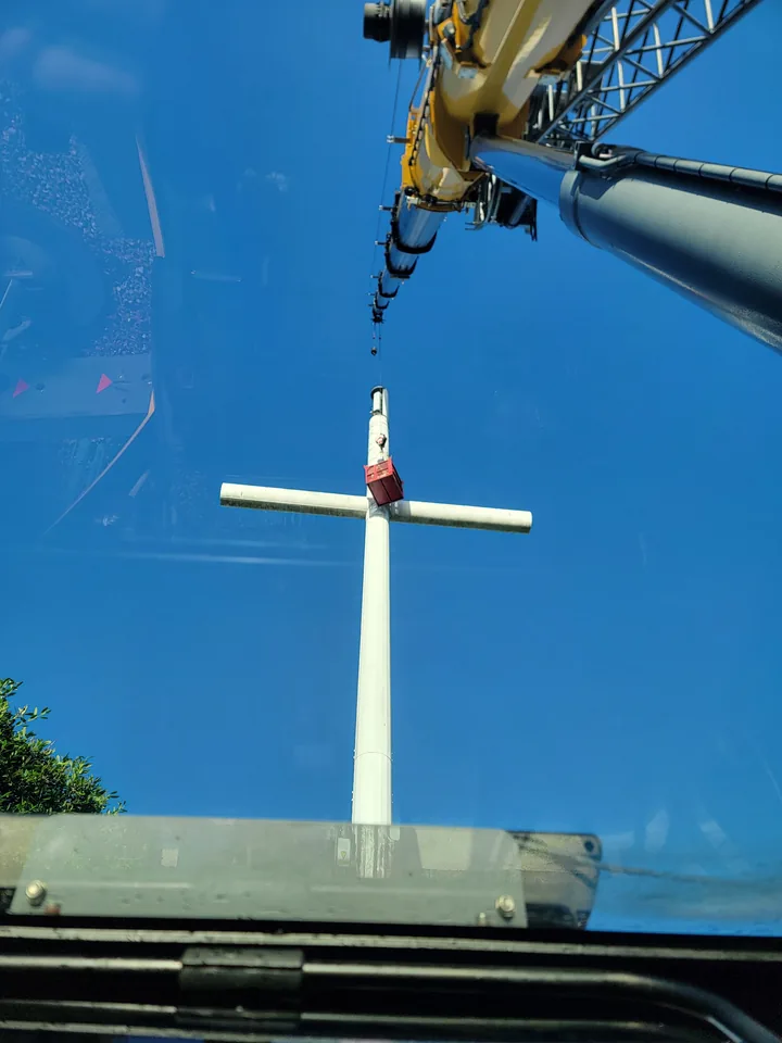 Upward view from a crane cab along a yellow boom toward a tall structure.