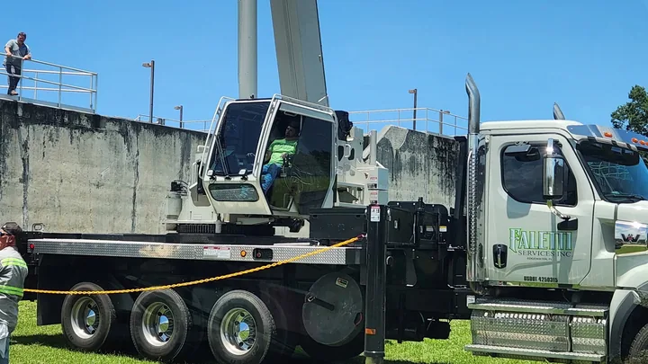 Person seated in the crane cab of a white Faletti truck.