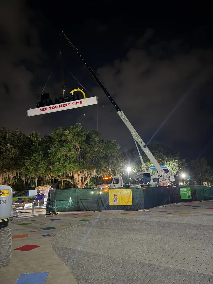White crane supporting a large sign at night.