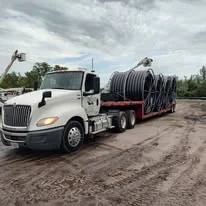 Small supplied photograph of a white tractor and trailer carrying coiled material.