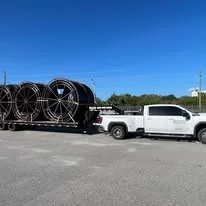 Small supplied photograph of a white pickup towing a trailer with coiled material.