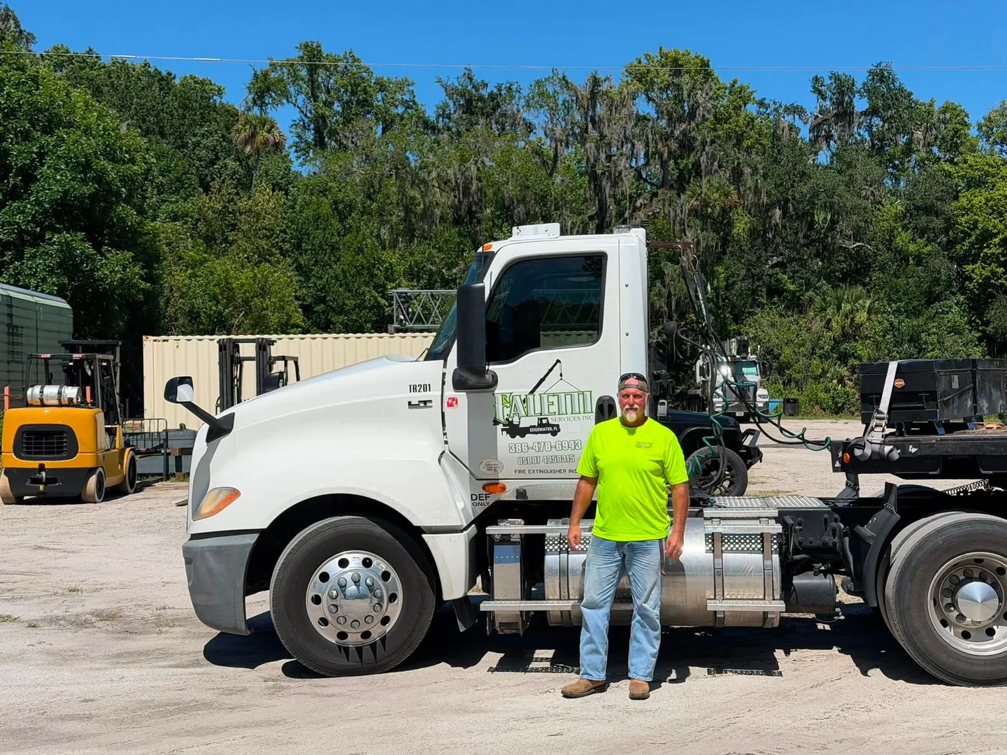 A person beside a white Faletti tractor truck in a yard.